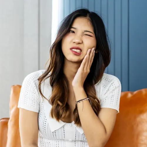 woman holding her cheek in pain